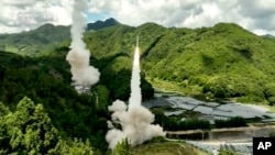 中国电视节目截屏，画面字幕：东部战区火箭军不对对台岛东部外海预定海域实施常导火力突击 全部精准命中目标。-美联社提供照片