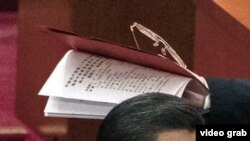 視頻截圖顯示，習近平叫來的工作人員手裡拿著那份不許胡錦濤在中共20大會場翻閱的人事名單。