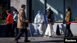 北京街头一名身穿防护服的大白坐在新冠核酸检测桌旁。（2022年10月23日）