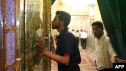 資料照片：一名伊朗男子正在親吻燈王之墓的大門。