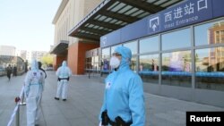 中國吉林省吉林市身穿防護服的警察站在停運的火車站進站口處。（2020年5月13日）