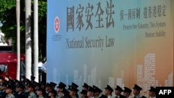 香港警察舉行升旗儀式與他們背後的國安法宣傳牌。（2020年7月1日）