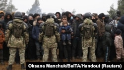 白俄羅斯軍人在白俄羅斯-波蘭邊境的一個臨時營地守衛，移民正聚集在一起等待領取人道主義援助物資。（2021年11月14日）