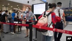 資料照：北京首都機場的工作人員檢查旅客們的COVID-19測試結果