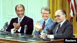 ແຟ້ມພາບ - ປະທານາທິບໍດີ ຈິມມີ ຄາຣ໌ເຕີສ ລົງນາມໃນສົນທິສັນຍາ ສັນຕິພາບ ຄ້າຍທະຫານ ແຄ້ມເດວິດ ຮ່ວມກັບນາຍົກລັດຖະມົນຕີ ອິສຣາແອລ ເມນາເຄມ ເບກິນ ແລະປະທານາທິບໍດີ ອີຈິບ ອັນວາຣ໌ ຊາດາຕ ທີ່ທຳນຽບຂ່າວ ເມື່ອວັນທີ 17 ກັນຍາ 1978.