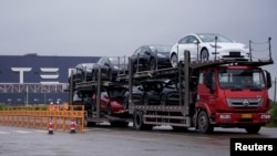 一辆大卡车运出特斯拉上海工厂出产的汽车。（2021年5月13日）