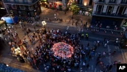 People gather at a memorial tribute of flowers, messages and candles to the victims on Barcelona's historic Las Ramblas promenade on the Joan Miro mosaic, embedded in the pavement where the van stopped after killing at least 13 people in Barcelona , Spain