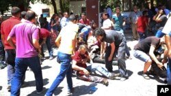 Люди помогают раненым после взрыва в городе Суруч, Турция, 20 июля 2015