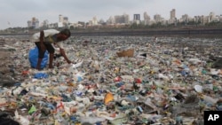 印度孟买布满垃圾的海滩上一名男子在捡拾塑料制品和其他可回收物品。（2018年6月4日）