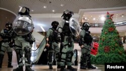 香港防暴警察在一個商場中站在一棵聖誕樹旁面對示威者。 （2019年12月24日）