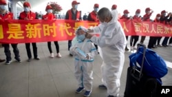 武漢解封，天河國際機場的旅客站在慶祝的標語橫幅旁。（2020年4月8日）