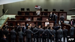 在香港的一次立法会会议上，亲民主议员(上)在一场关于禁止侮辱中国国歌的法律的辩论中被保安（下）阻挡。(2020年6月4日)
