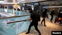 资料照：香港一名抗议者正在打碎九龙一家商场的玻璃围栏。（2019年11月12日）