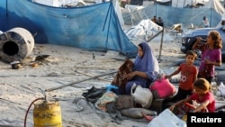 在加沙地帶南部汗尤尼斯的 Al-Mawasi 地區，以色列襲擊了一個為流離失所者提供庇護的帳篷營地，一名巴勒斯坦婦女在現場翻看兒童身邊的物品。（2024年9月10日）