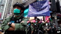 資料照片：香港警方在慶祝中國共產黨建立中華人民共和國的節日期間在銅鑼灣街向抗議者舉出警告旗幟。 (2020年10月1日)