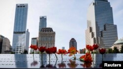 罹難者親屬在世貿中心雙子樓遺址現在是兩個方形紀念水池，插上鮮花。