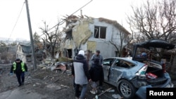 资料照片：人们站在俄罗斯空袭基辅后摧毁的房屋旁边。(2022年12月31日)