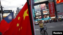 一名台灣婦女騎車從台北街頭舉行的台灣親中國組織呼籲和平統一的一個集會前駛過。（2016年5月14日）