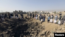 一些也門人聚集在沙特空襲造成的一個大坑旁邊