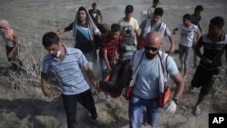 7月21日巴勒斯坦人在以色列跟加沙交界处跟以色列军人发生冲突。图中巴勒斯坦医护人员和抗议者疏散一名冲突中受伤的男子。