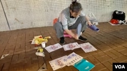 香港社運人士雷玉蓮趁農曆驚蟄到灣仔鵝頸橋底”打小人”，抗議新一份財政預算案”肥上瘦下”，呼籲立法會議員憑良心投下反對票。(美國之音)