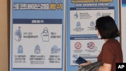 在首爾景福宮，戴著口罩的行人走在預防冠狀病毒預防措施的橫幅前。 （2020年8月16日）