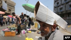 An Iraqi street vendor protects his head from the sun by using a piece of cardboard as a hat during a heat wave in the capital Baghdad, June 14, 2019. 