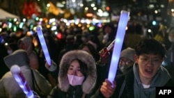 2024 年 12 月 7 日，人们在首尔国民议会外举行抗议活动要求罢免韩国总统尹锡烈。