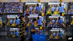 一名婦女和男孩走過北京商場的電視銷售區。（2018年7月11日）