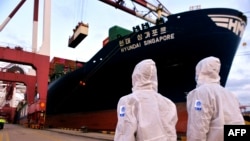 身穿防護服的中國海關人員在山東省青島港檢查一艘貨輪。（2020年11月16日）