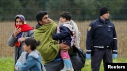 在斯洛文尼亚的兰达瓦，一个移民家庭正在走向克罗地亚和斯洛文尼亚过境点附近的一个登记站。(2015年10月17日)