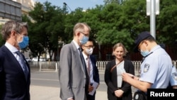 一名中國警察在北京市第二人民法院外查看澳大利亞駐華大使傅關漢(Graham Fletcher)的身份證件。（2021年5月27日）