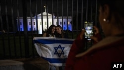 白宮2023年10月9日晚亮出以色列國旗的燈光，支持者們在大門前留影。（法新社）