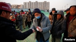 北京一处建筑工地里一个工头给打工工人发工资过年。（2021年2月6日）