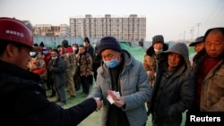 北京一處建築工地裡一個工頭給工人發工資。（2021年2月6日）