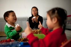 中國官方2011年10月29日宣布允許所有夫妻生育二胎。圖為浙江諸暨35歲的王女士和她的兩個孩子在家中。 (2011年10月17日資料照。)