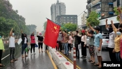 資料照片：反對軍政府政變的抗議人士在示威活動中準備點燃一面中國國旗以表達不滿。(2021年4月5日)