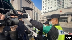 資料照片：一名警察擋住記者的鏡頭阻止拍攝審訊公民記者張展的上海浦東新區法院外景。（2021年12月28日）