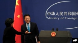 资料照片：中国外交部发言人华春莹引导新任发言人赵立坚走入例行记者会会场。（2020年2月24日）