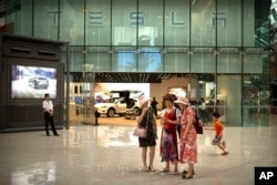 2018年7月5日，一些女士在北京一家高檔購物中心的特斯拉展廳外觀看智能手機