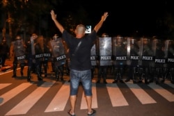 在当局宣布紧急状态后,一名要求民主的抗议者在曼谷面对警察打出三指礼的抗议手势。(2020年10月15日)