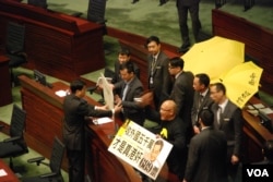 泛民主派立法會議員陳偉業(右)及陳志全在議會內，舉起諷刺梁振英的標語，被保安人員抬離會場。（美國之音湯惠芸攝）