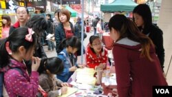 有家長帶同年幼子女參觀中國維權律師關注組的攤位，了解中國維權律師子女被當局剝奪人權的狀況 (美國之音湯惠芸)