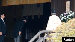 日本首相安倍晋三12月26日参拜靖国神社时在神道祭司旁鞠躬。