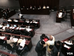 香港政務司司長林鄭月娥在立法會簡介港府第一階段政改諮詢報告，人民力量陳偉業議員上前抗議她「一錘定音」假諮詢，被保安人員帶離會議室。