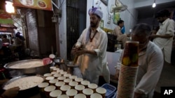 资料照片：2015 年 7 月 7 日星期二，巴基斯坦拉瓦尔品第，一名巴基斯坦小贩在为穆斯林斋月黎明前的餐食“sehri”准备牛奶拉西。