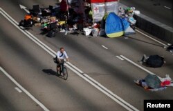 一名男子騎單車穿越示威人士佔領的馬路返回政府總部上班。