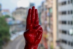 一名反军事政变抗议者用红漆染红的手举手行三指礼。（2021年4月6日）