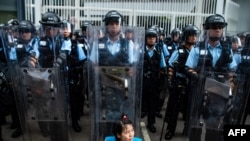 2019年6月12日，香港立法會外，一名抗議者坐在防暴警察面前。