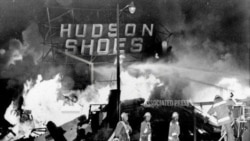 资料照片- 消防员在洛杉矶瓦茨区的骚乱中与一家鞋店发生的大火搏斗。（1965年8月14日）美联社